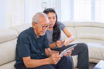 Old man with his daughter playing tablet at home