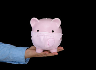 A man holding a piggy bank wearing a mask in front of a black background
