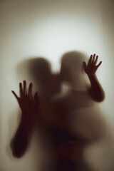 Concept shadow of Mother and child kissing the matte glass blurry hand and body soft focus