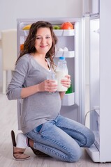 Pregnant woman near fridge looking for food and snacks