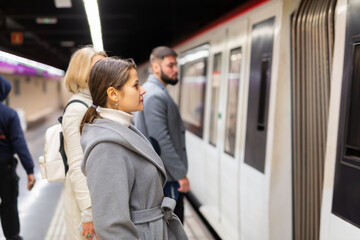 Attractive brunette waiting for train on platform of underground station ..