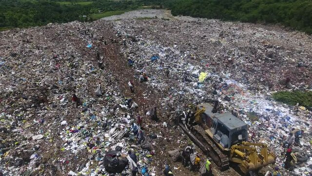 Excavator pushes waste at Duquesa landfill, Dominican Republic. Aerial top view