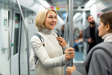 Two women passengers talking in subway car on way to work. High quality photo