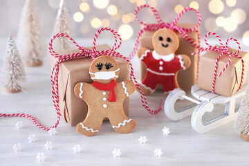Gingerbread man cookies with protective face mask and Christmas gift boxes on Christmas decoration table.  Christmas and new year concept in new normal. マスクをしたジンジャーマンクッキー クリスマスギフト