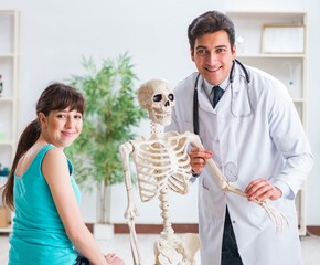 Doctor showing type of injury on skeleton to patient