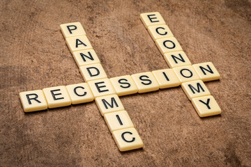 pandemic and economy recession crossword in ivory letters against textured handmade bark paper, business crisis due to covid-19 outbreak