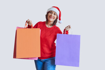 Happy adult woman in a santa hat, with a New Year's bag in her hands. Christmas, new year concept.