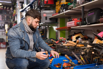 Fototapeta na wymiar Adult consumer is choosing various hand tools in store