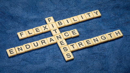 endurance, flexibility, strength - fitness training goals concept, crossword with ivory letter tiles on textured blue paper