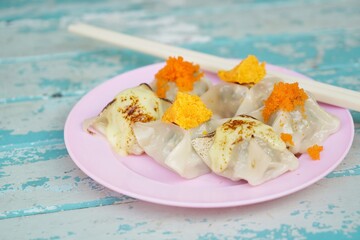Wontons with topping without soup on pink dish