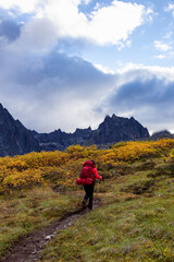 Obraz premium Girl Backpacking on Scenic Hiking Trail surrounded by Rugged Mountains during Fall in Canadian Nature. Taken in Tombstone Territorial Park, Yukon, Canada.