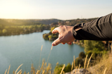 Close-up of a hand pointing to a lake within a nature reserve