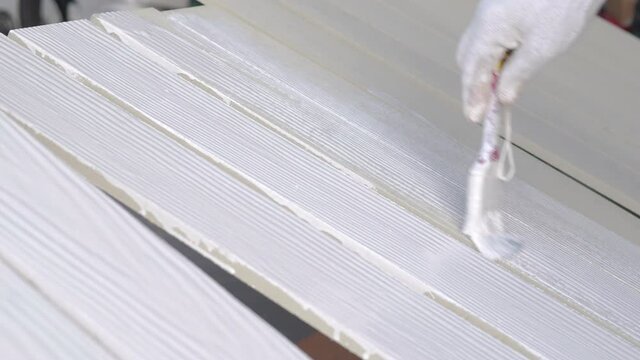 Close-up workers painted white on wood for fencing