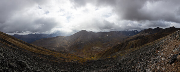 Fototapeta na wymiar Panoramic View of Scenic Rocky Landscape, Valley and Mountains on a Cloudy Fall Day in Canadian Nature. Taken in Tombstone Territorial Park, Yukon, Canada.