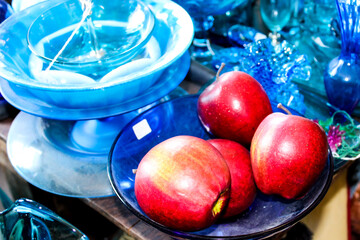 Bright red apples sitting with blue glass kitchenware 