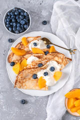 Crepes with yoghurt, berries and peaches