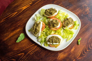 Mozzarella cheese and Pesto Salad cherry tomatoes and arugula pesto bruschetta on wood background