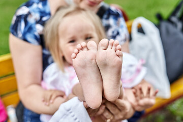 Mom holds baby and shows daughter bare feet - 386560073