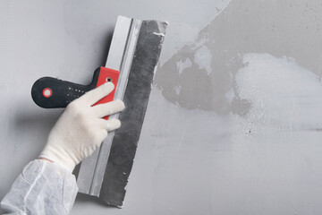 master's hands apply the finishing putty on the concrete wall, close-up, there is a place for the...