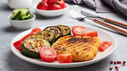 Schnitzel of chicken and zucchini cooked on the grill. Fresh tomatoes on a plate. Ready delicious dinner lunch.