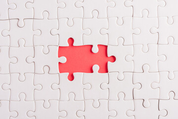 Top view flat lay of paper plain white jigsaw puzzle game texture incomplete or missing piece, studio shot on a red background, quiz calculation concept