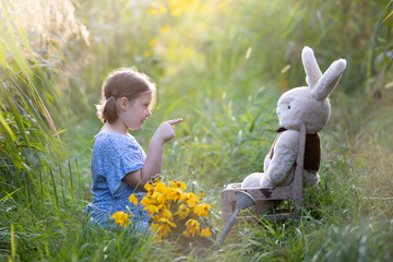 Adorable little girl with her teddy in the grass. Outdoor education concept.