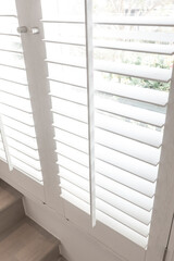 Closeup view of window with horizontal blinds. White Roller Blinds or Louver curtains at the glass window