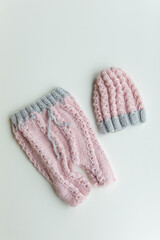 Various colors and types of cotton clothing, knitted newborn clothes and newborn hats on a white background.