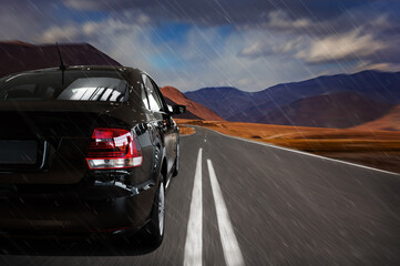 Close-up of a black car on the highway. travel by car. high-speed road along the mountains in the rain