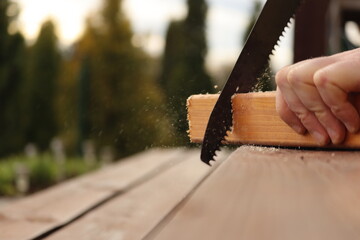 person cutting wood with handsaw