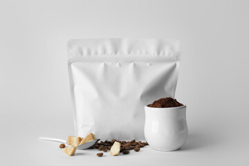 Blank coffee bag, cup with beans and sugar on light background