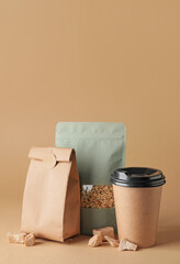 Blank coffee bags and cup on color background
