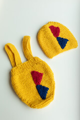 Various colors and types of cotton clothing, knitted newborn clothes and newborn hats on a white background.