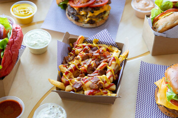 Take out burger restaurant table setting with poutine cheese & bacon loaded fries.