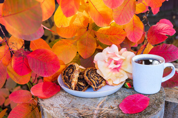 Obraz na płótnie Canvas Cup of coffee and cookies on a wooden stump among autumn leaves as breakfast in nature