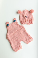 Various colors and types of cotton clothing, knitted newborn clothes and newborn hats on a white background.