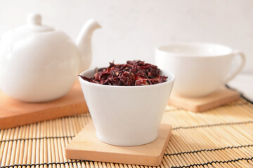 Bowl with dry hibiscus tea on table
