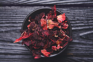 Bowl with dry hibiscus tea on table