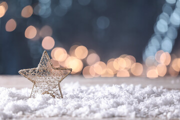 Christmas decor and snow on table against blurred lights
