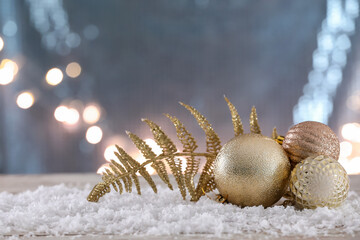 Christmas decor and snow on table against blurred lights