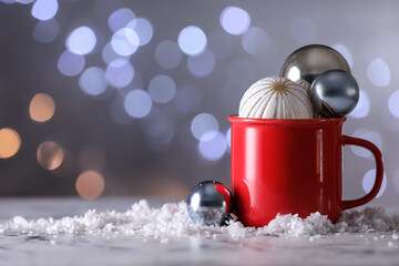 Cup with Christmas decor on table against blurred lights