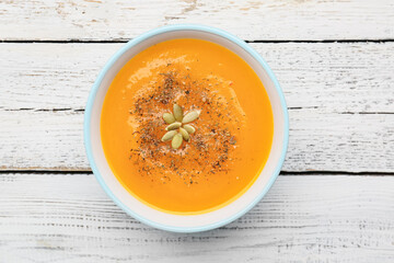 Tasty pumpkin cream soup in bowl on table
