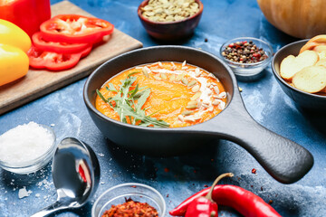Tasty pumpkin cream soup in bowl on color background