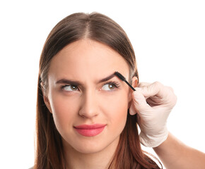 Naklejka premium Young woman undergoing eyebrow correction procedure on white background