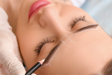 Young woman undergoing eyebrow correction procedure in beauty salon, closeup
