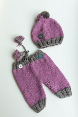 Various colors and types of cotton clothing, knitted newborn clothes and newborn hats on a white background.