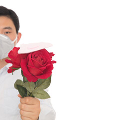 A man wearing a mask holds a rose and the mask on it