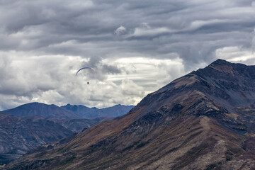 Paraglider flying over Scenic Mountain Range in Canadian Nature. Taken in Tombstone Territorial Park, Yukon, Canada.