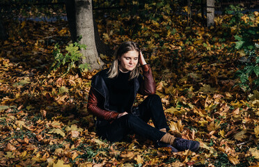 young woman autumn landscape red yellow maple leaves, in an orange knitted warm sweater