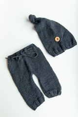 Various colors and types of cotton clothing, knitted newborn clothes and newborn hats on a white background.